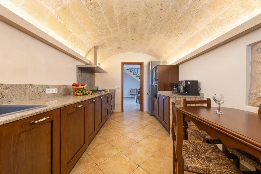 Cocina y comedor con gabinetes de madera y una mesa.