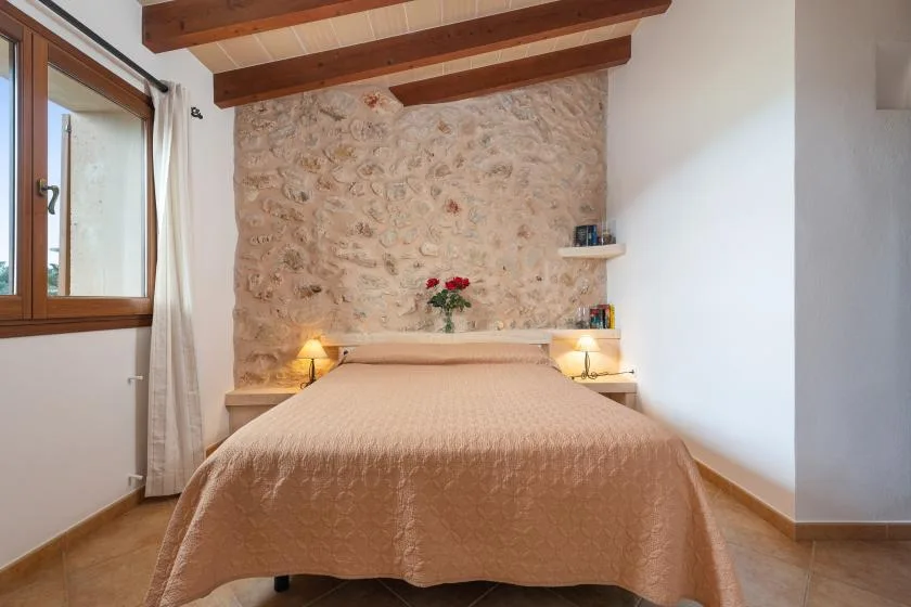 Un dormitorio con una cama bajo vigas de madera a la vista.