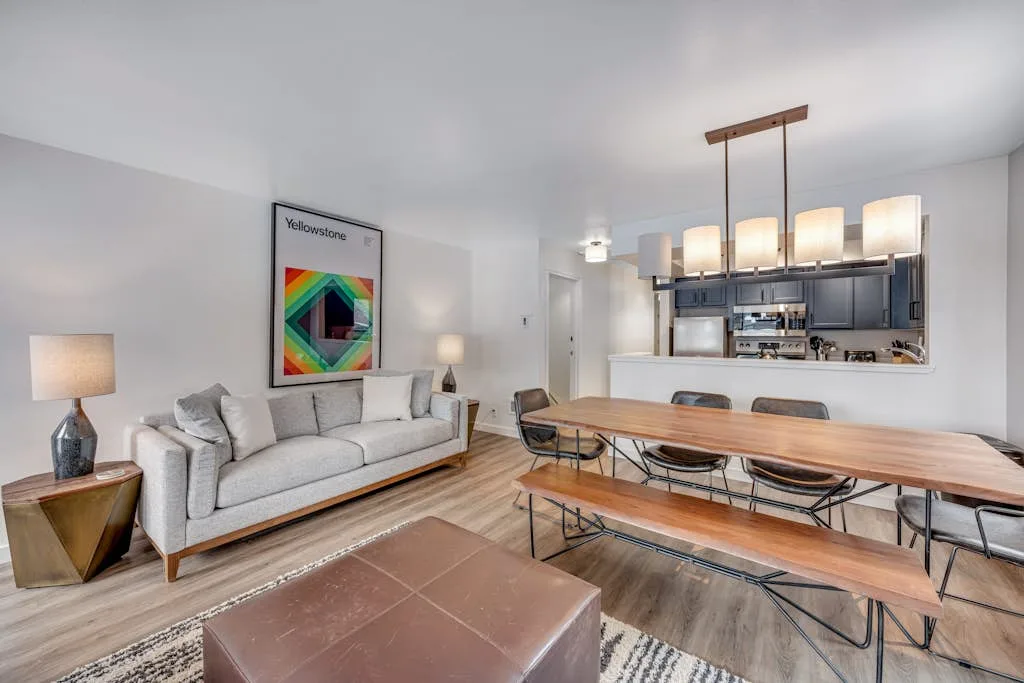 A bright open-plan living and dining area with a sofa and long wooden table.