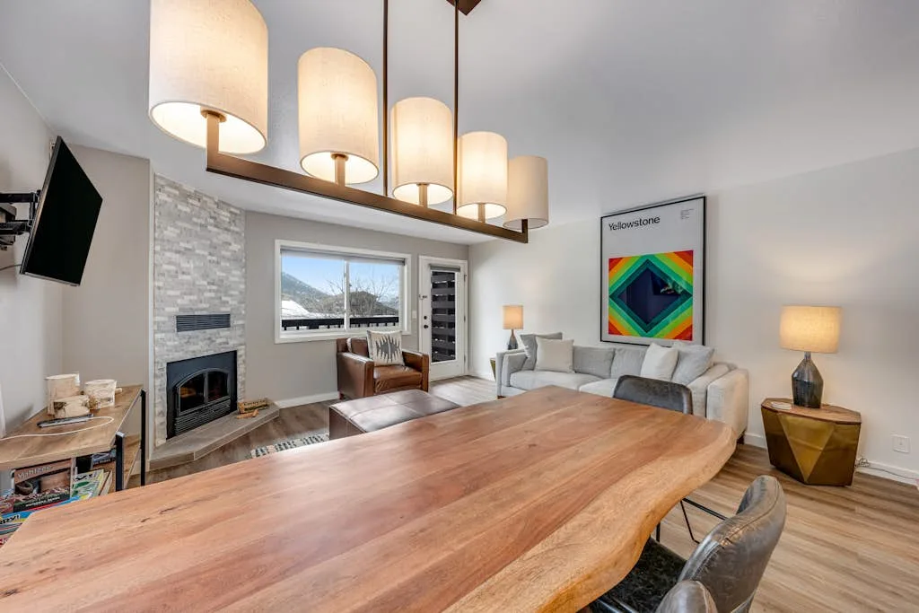 A bright living and dining area features a long wooden table and seating.