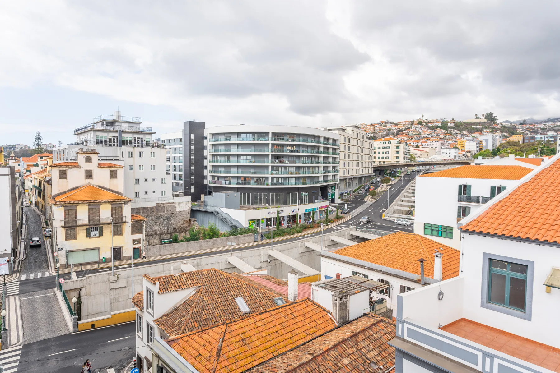 Cityscape of Funchal with buildings, rooftops, and a cloudy sky.