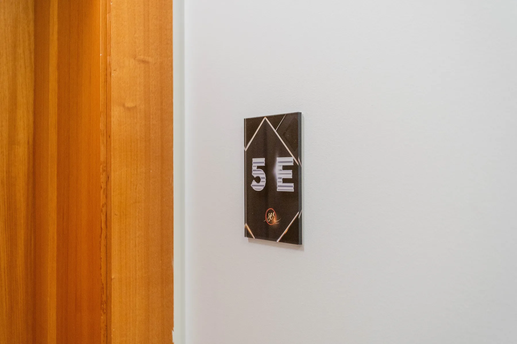 A hallway wall beside a wooden door has a small dark plaque.