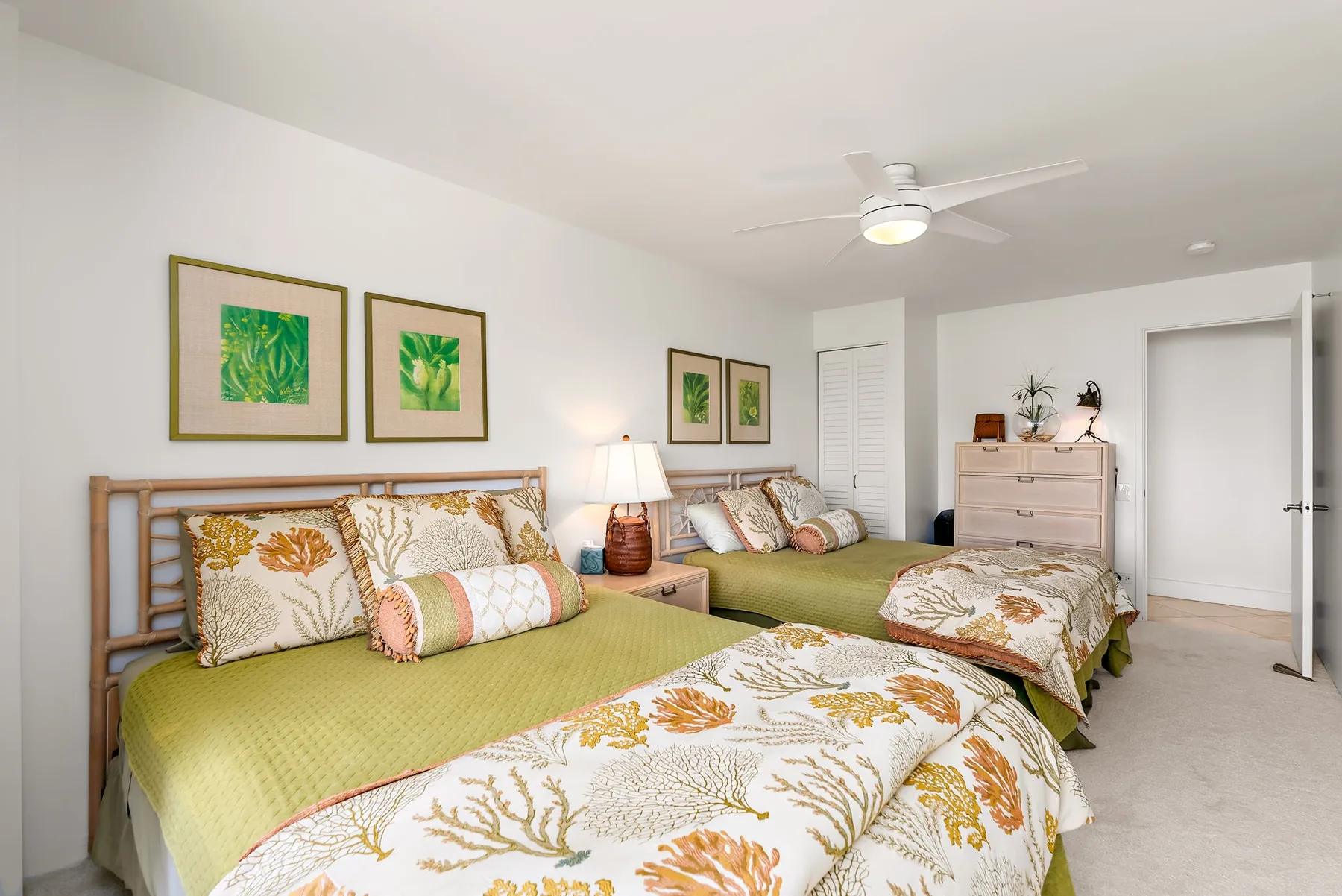 Un dormitorio luminoso con dos camas vestidas con ropa de cama floral y láminas botánicas enmarcadas.
