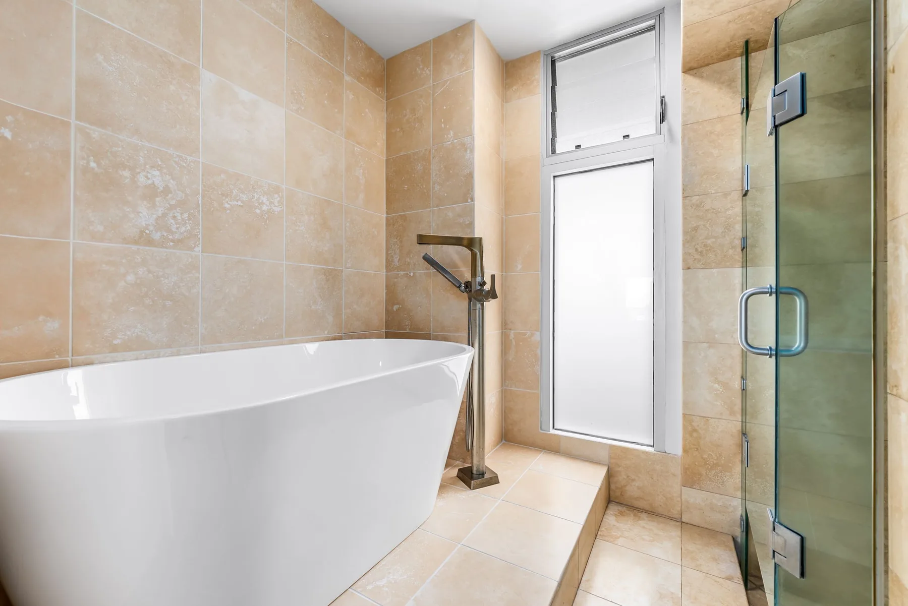 Un baño de azulejos con bañera exenta y ducha de vidrio.
