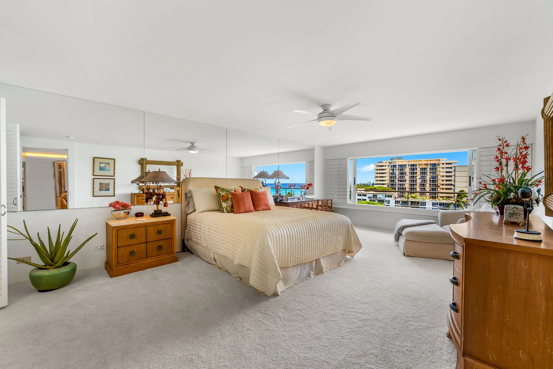 Un dormitorio luminoso con una cama grande, asientos y ventanas amplias.