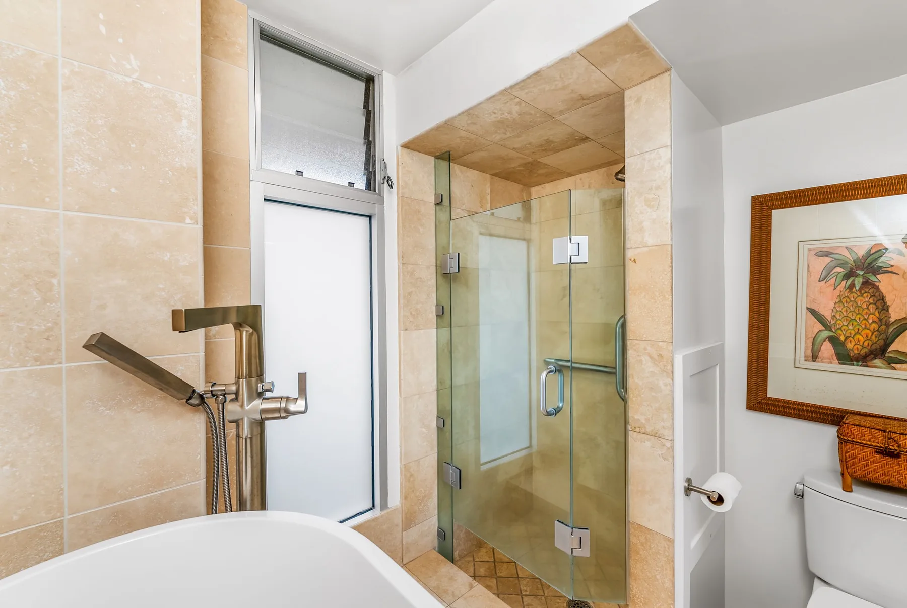 Un baño revestido de azulejos cuenta con ducha de vidrio, bañera e inodoro.