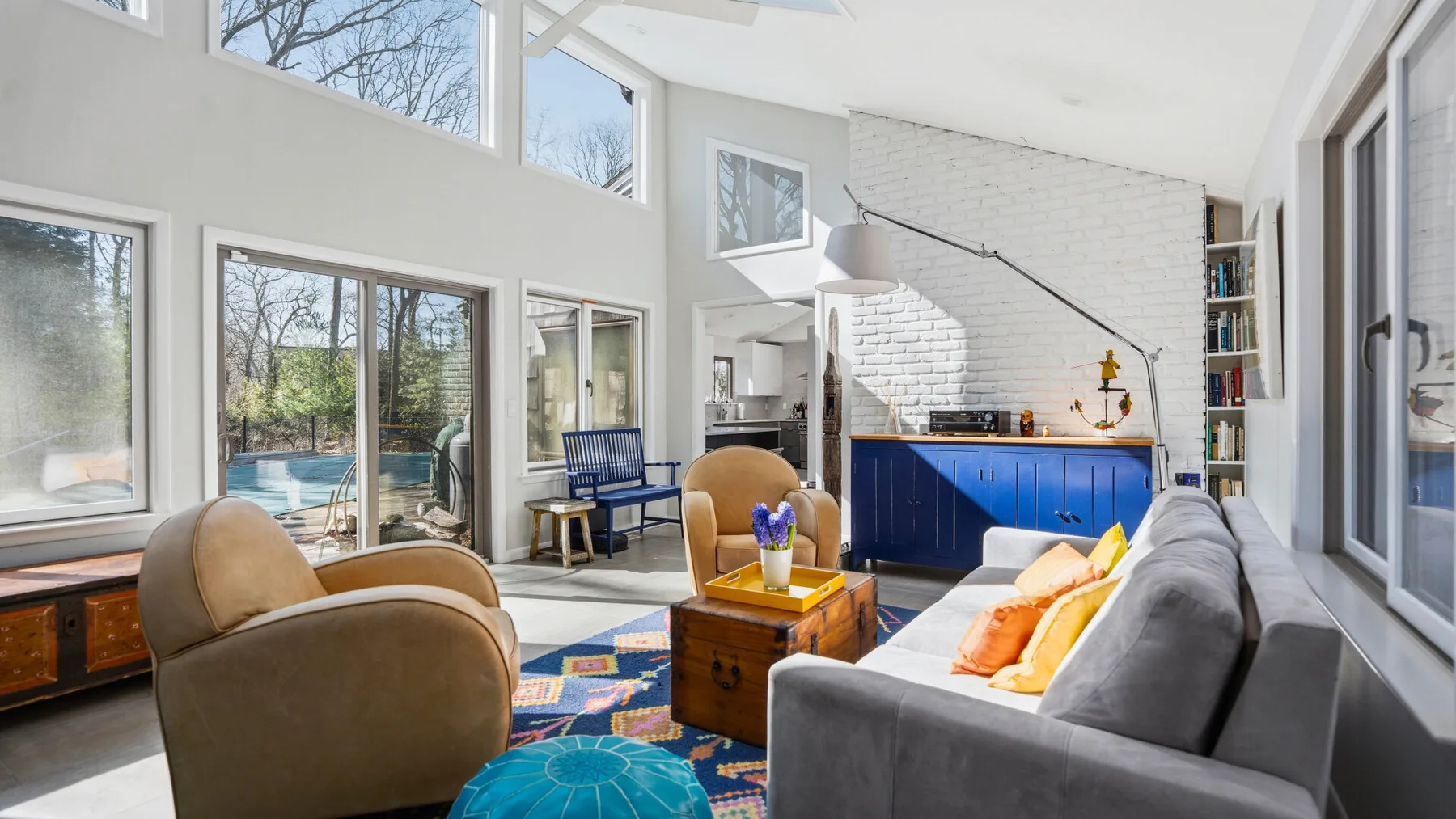 A bright living room with seating around a colorful rug and a blue kitchen island.
