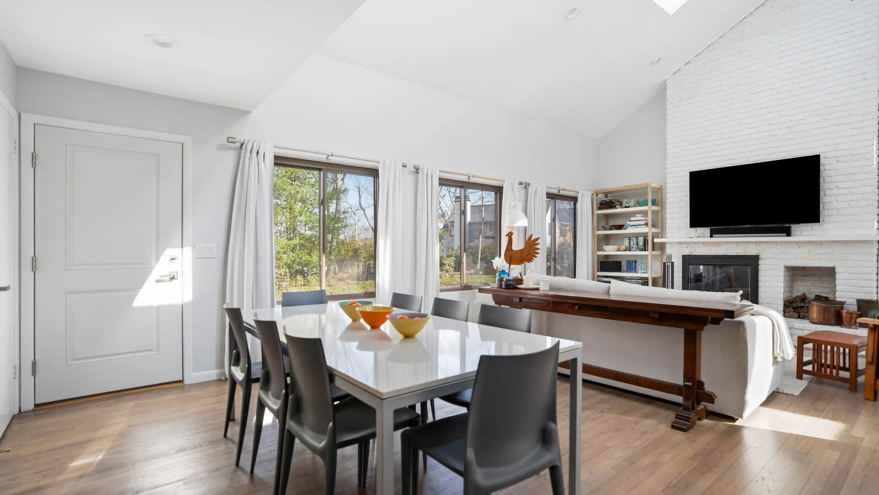 A bright dining area with a table and chairs beside large windows.