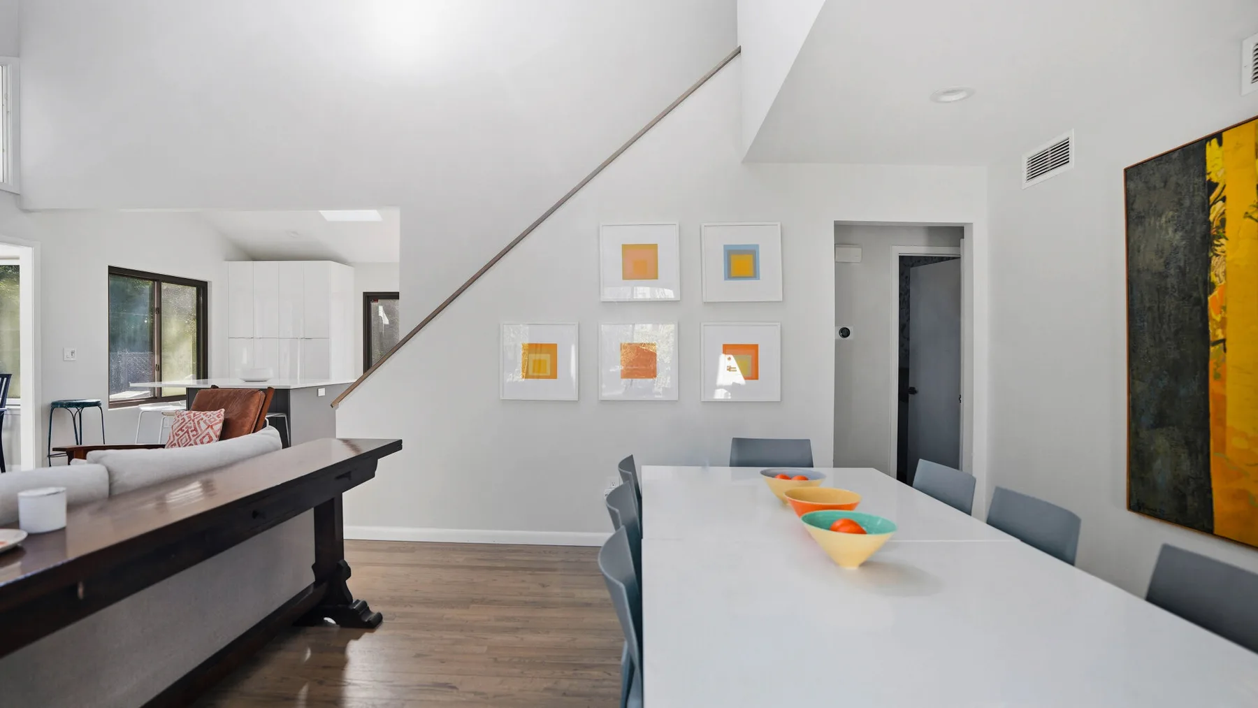 A bright open-plan dining and kitchen area has colorful bowls on the table.