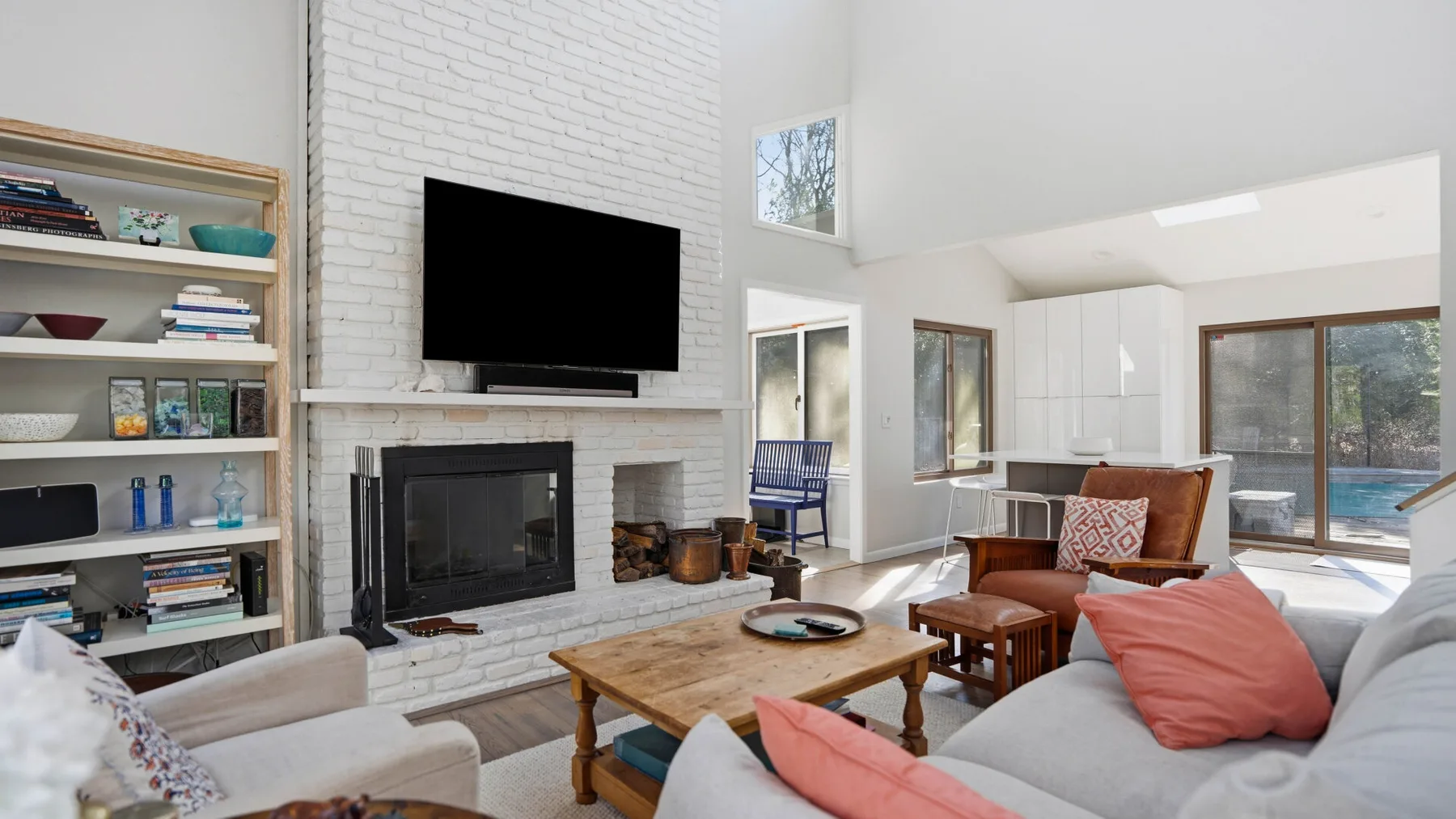 Una sala luminosa con chimenea, televisor y asientos alrededor de una mesa de centro.