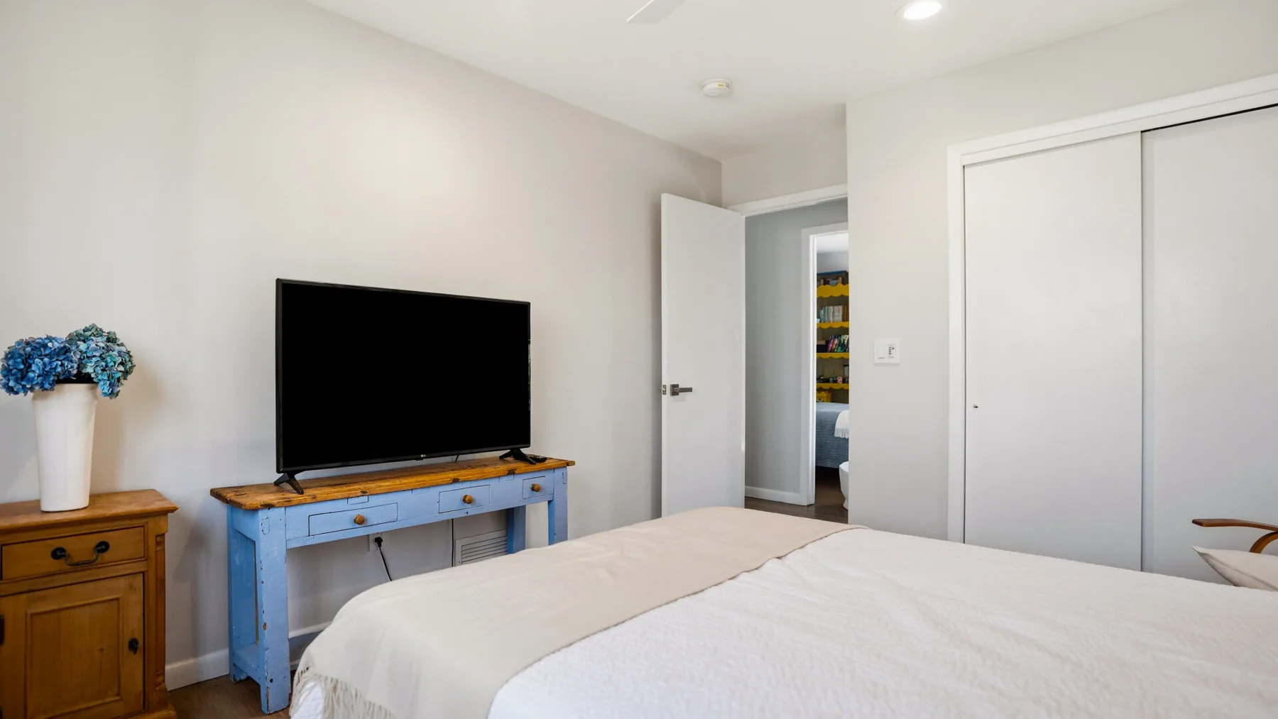 A bedroom with a bed, television, and open doorway.