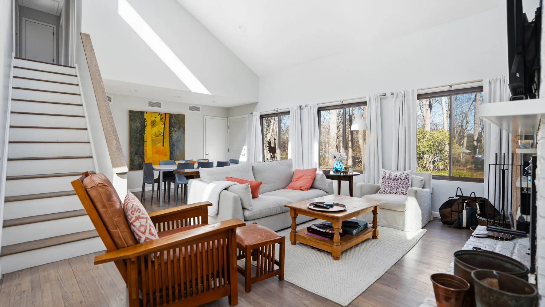 A bright living room with seating around a wooden coffee table and large windows.