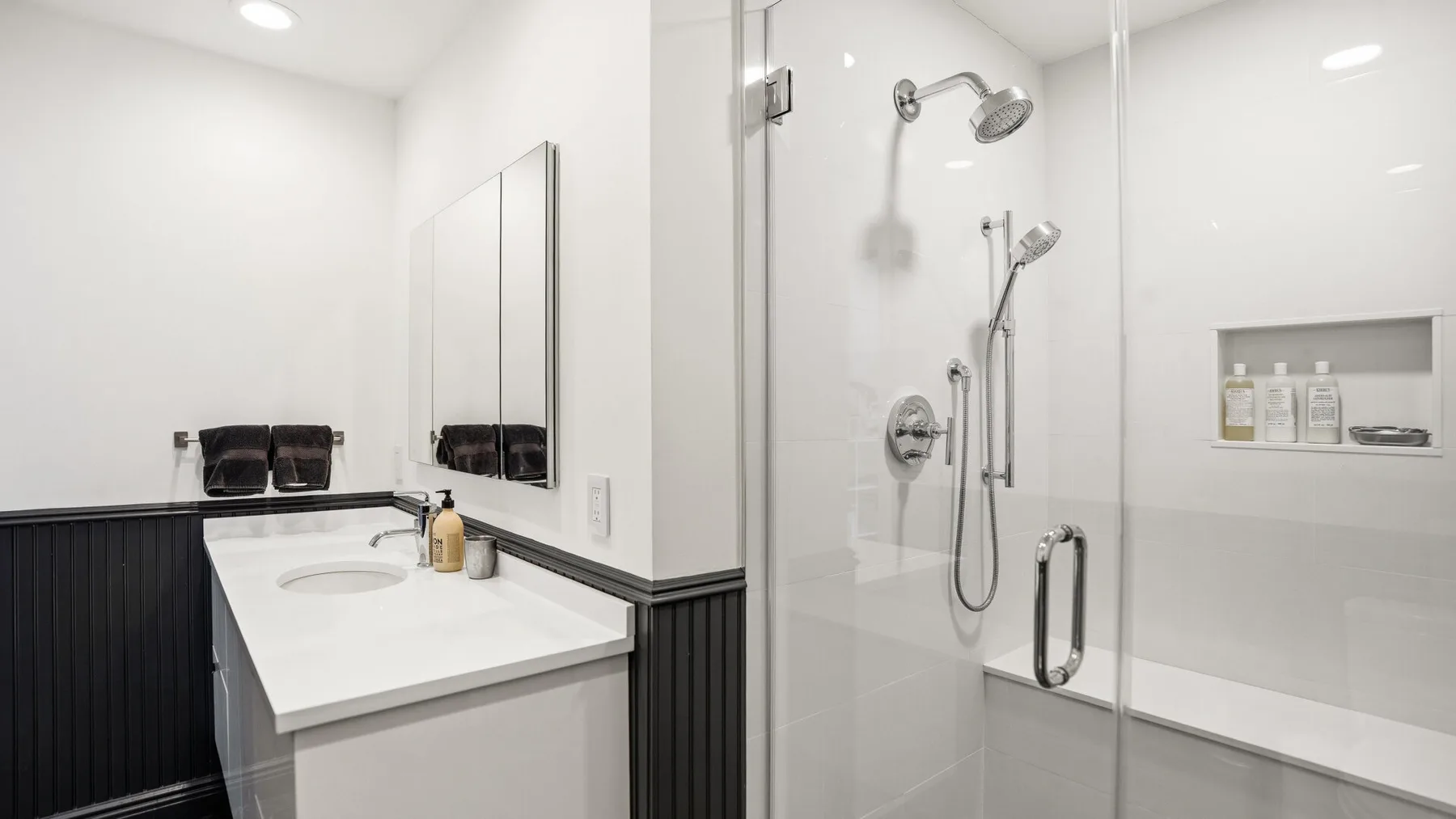 A bright bathroom with a white vanity and glass-enclosed shower.