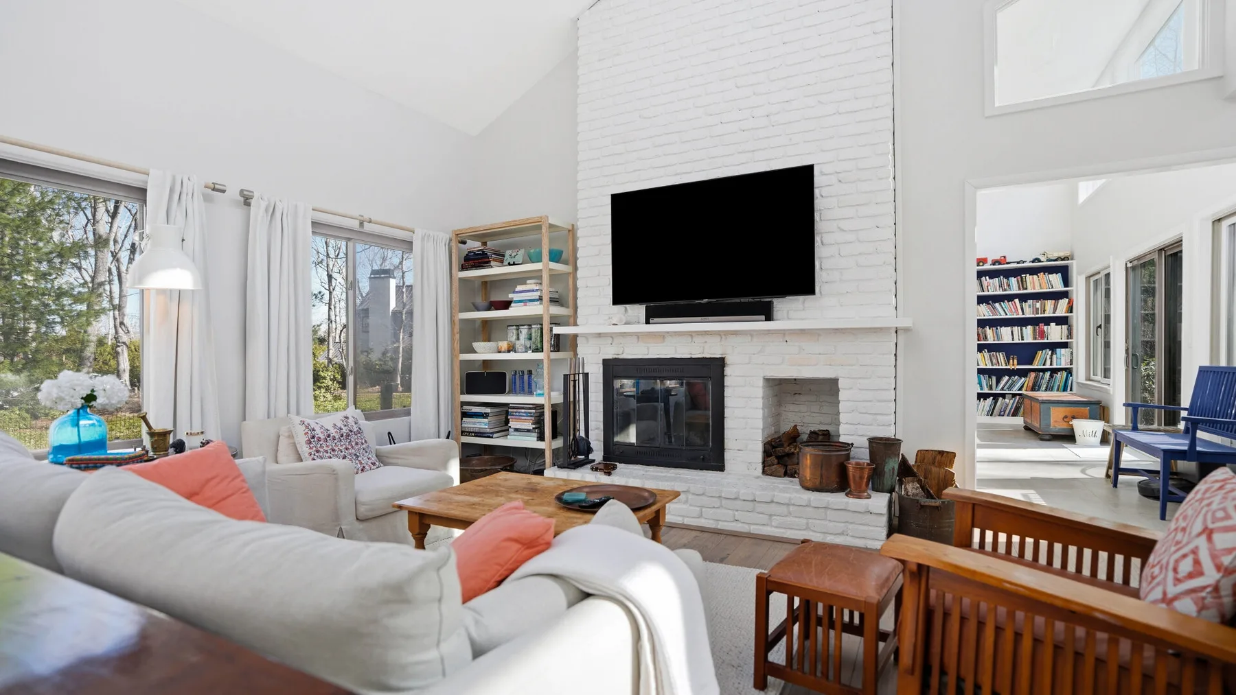 A bright living room with seating arranged around a fireplace and television.