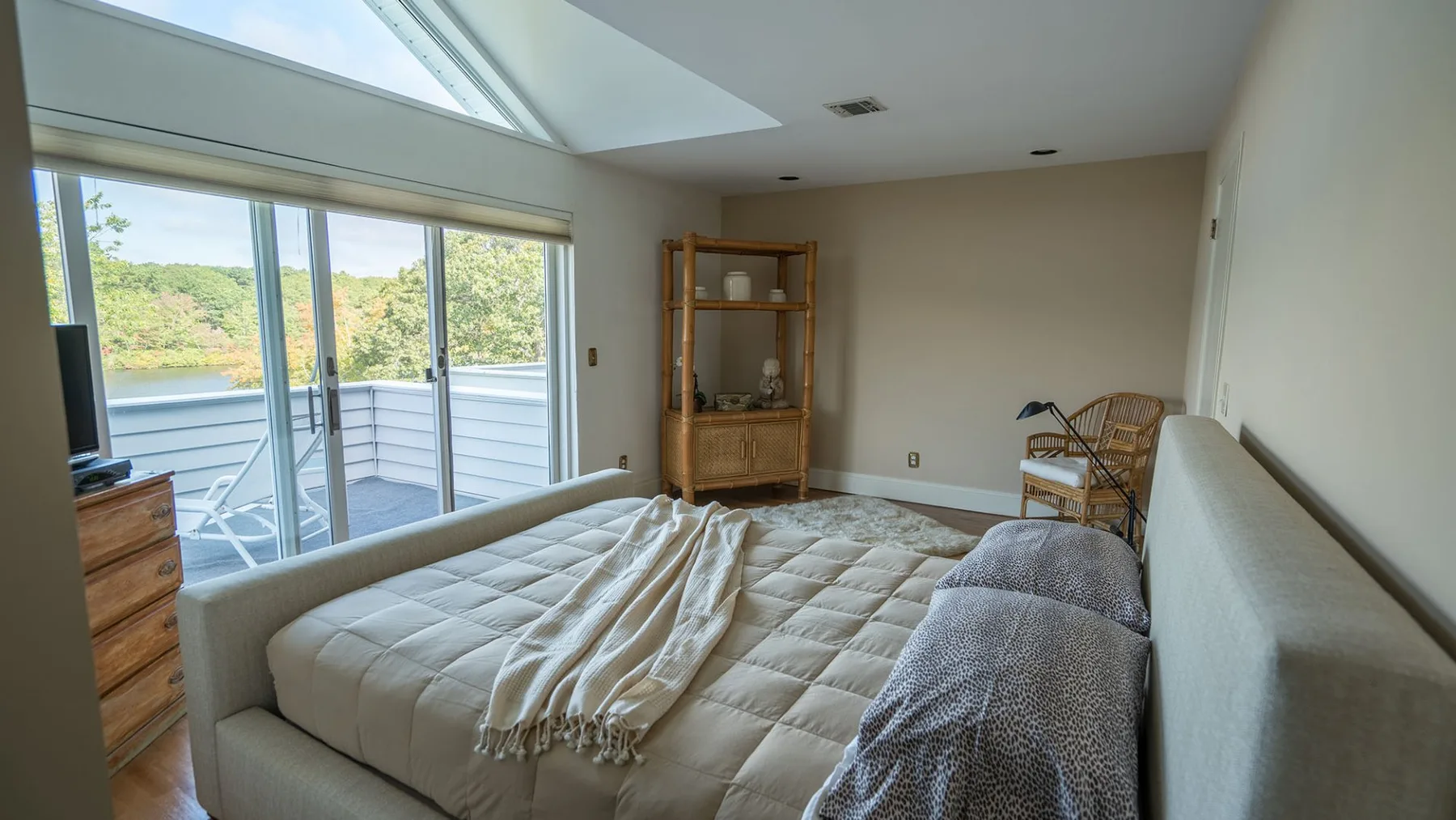 Un dormitorio con una cama junto a grandes ventanas y una estantería de madera.