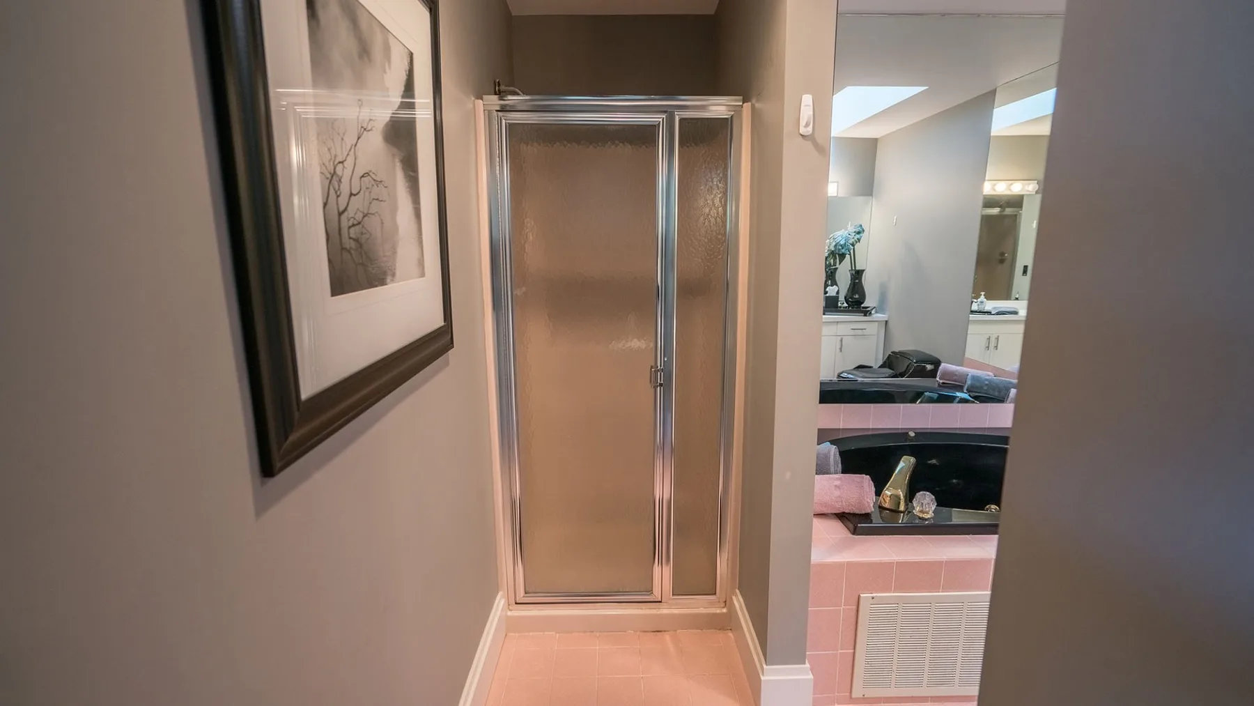 Al fondo de la puerta se ve un tocador de baño con lavabo y espejo.