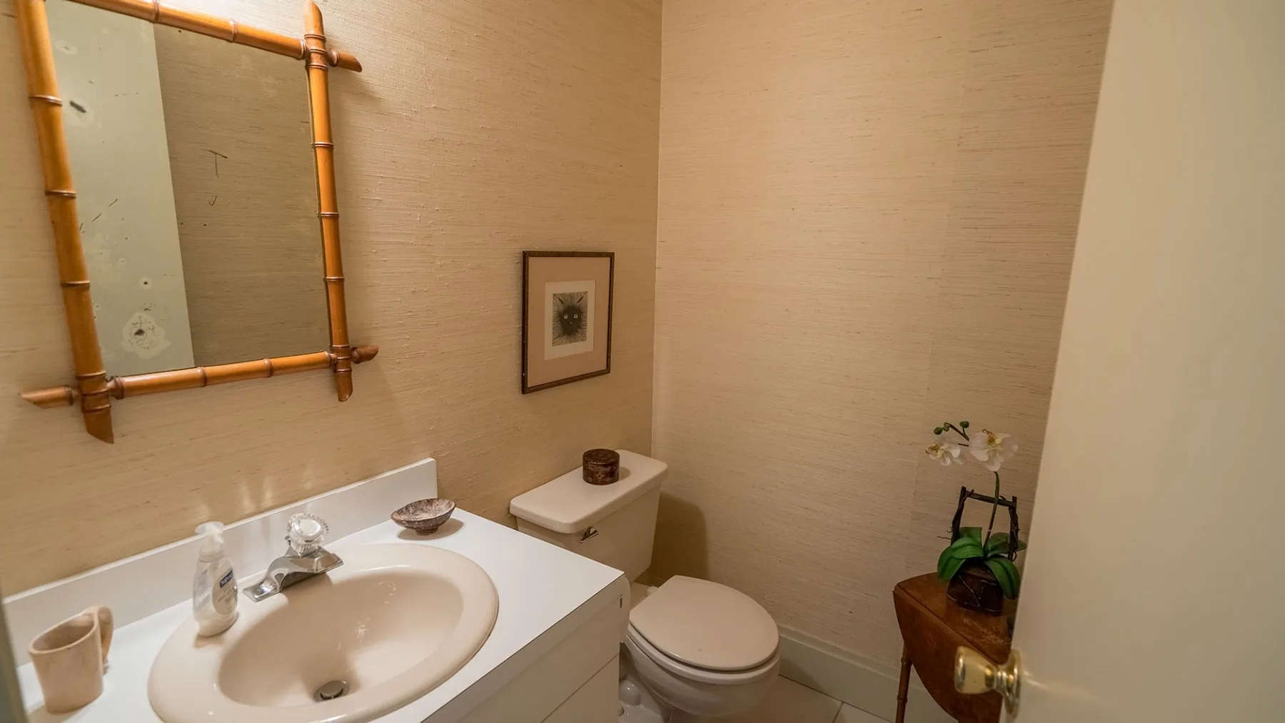 Un baño con lavabo, inodoro y una pequeña planta en maceta.