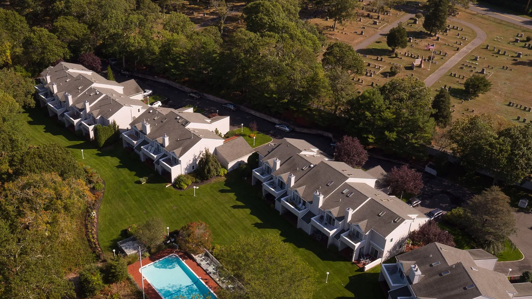Vista aérea de un largo edificio residencial junto a un césped ajardinado y una piscina.