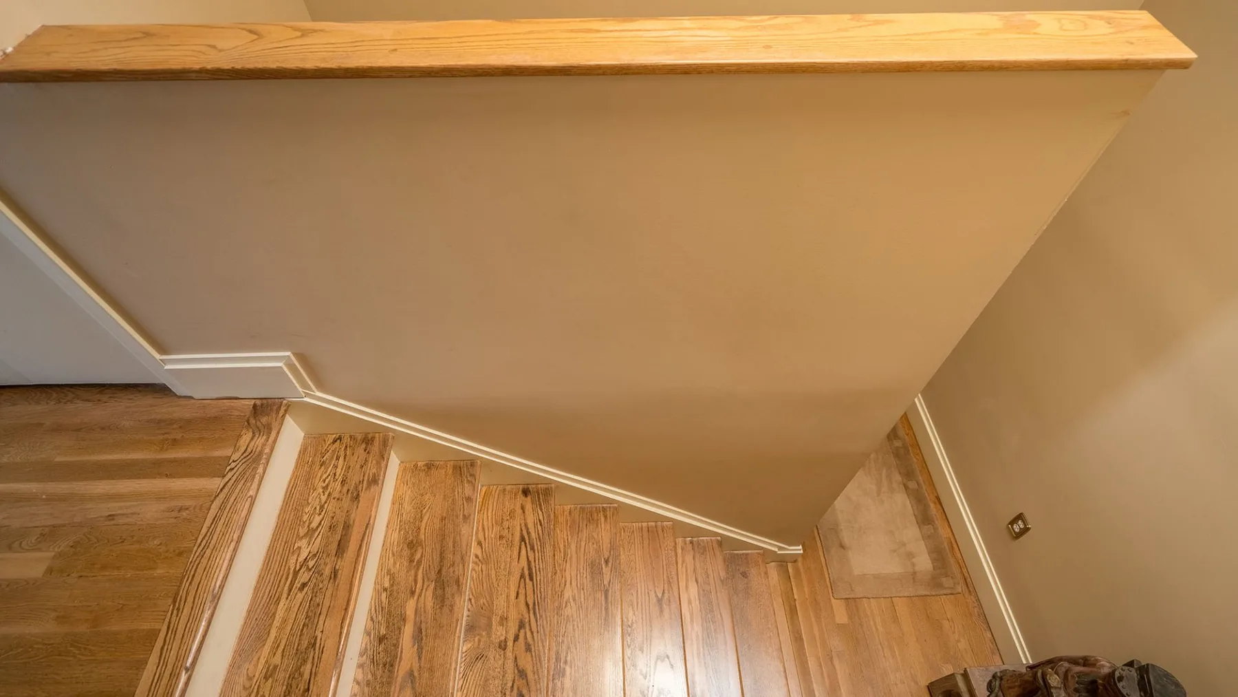 Un suelo de madera junto a un gran tabique inclinado en un pasillo interior.