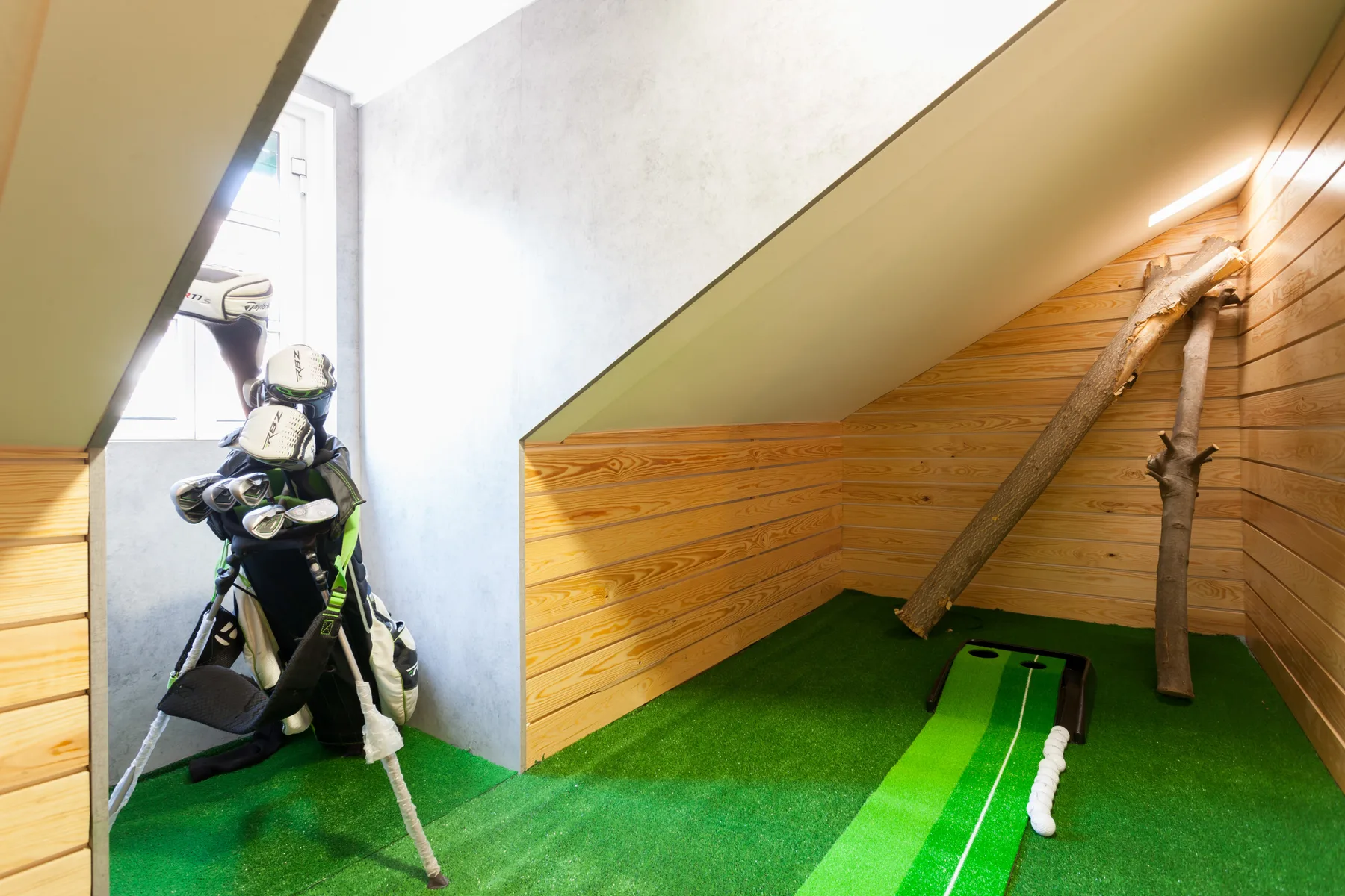 A golf practice area with green flooring and a golf bag beside the opening.