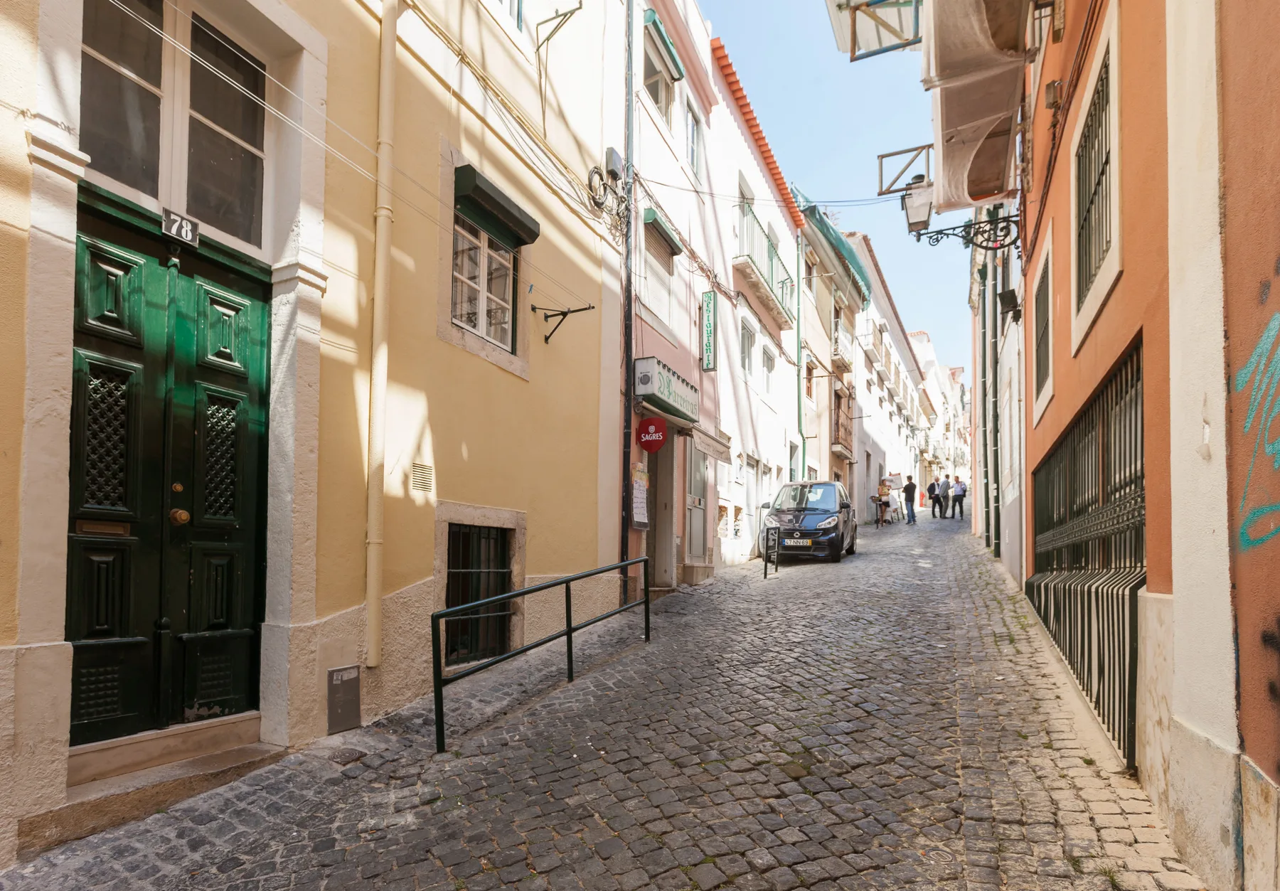 A narrow cobblestone street runs between closely spaced buildings.