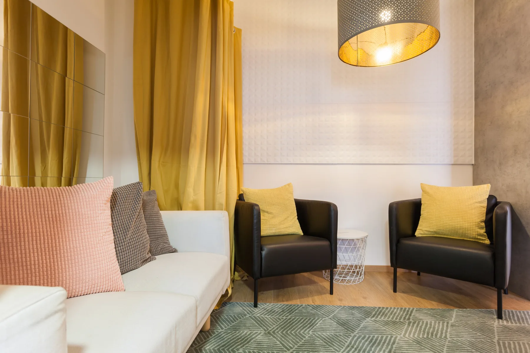 A living room with seating, mustard curtains, and a patterned rug.