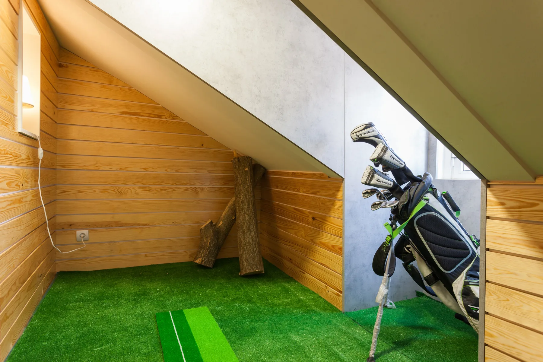 A small indoor golf practice area with green turf and a golf bag.