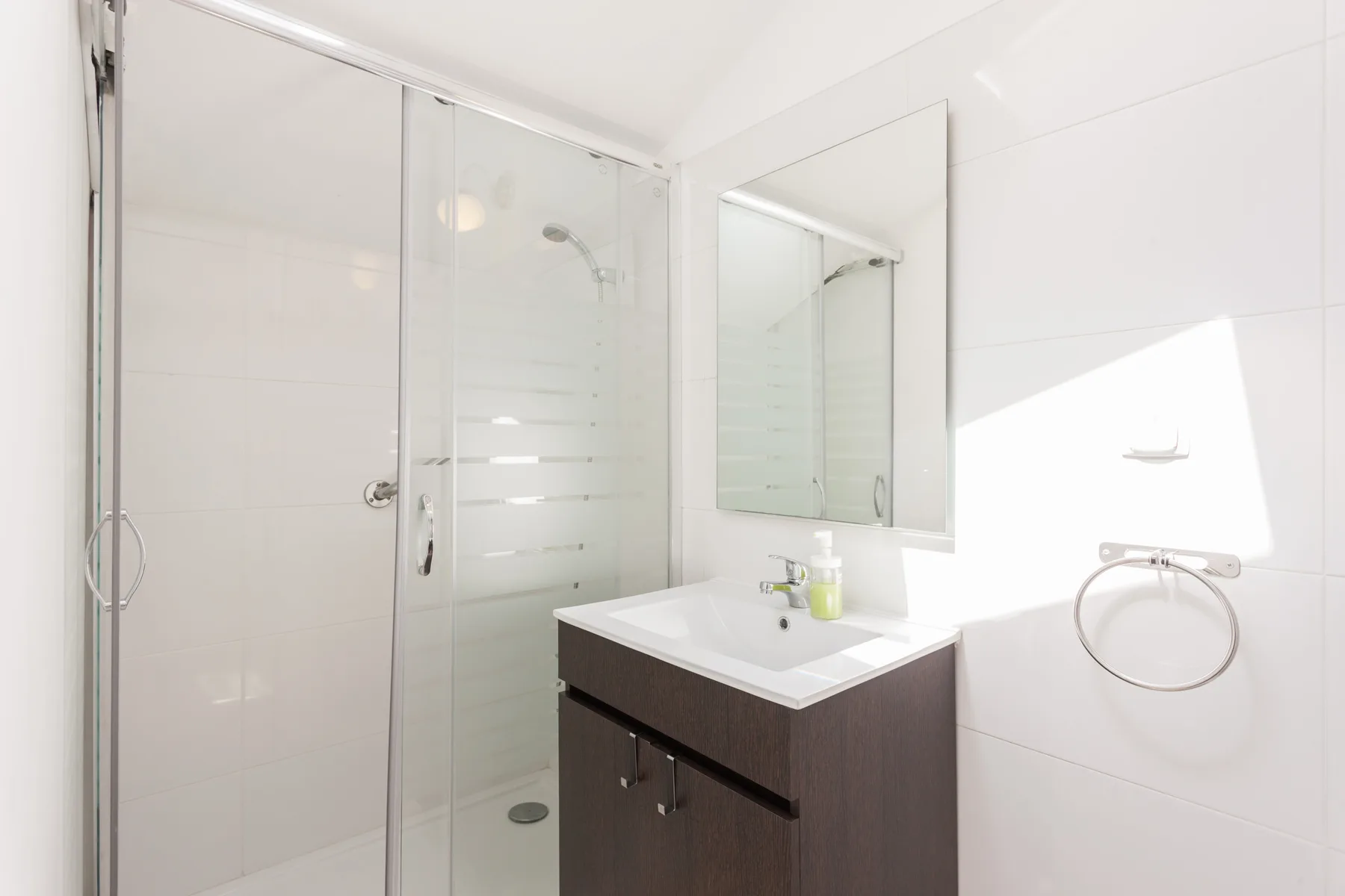 A bright bathroom with a glass shower and a sink beneath a mirror.