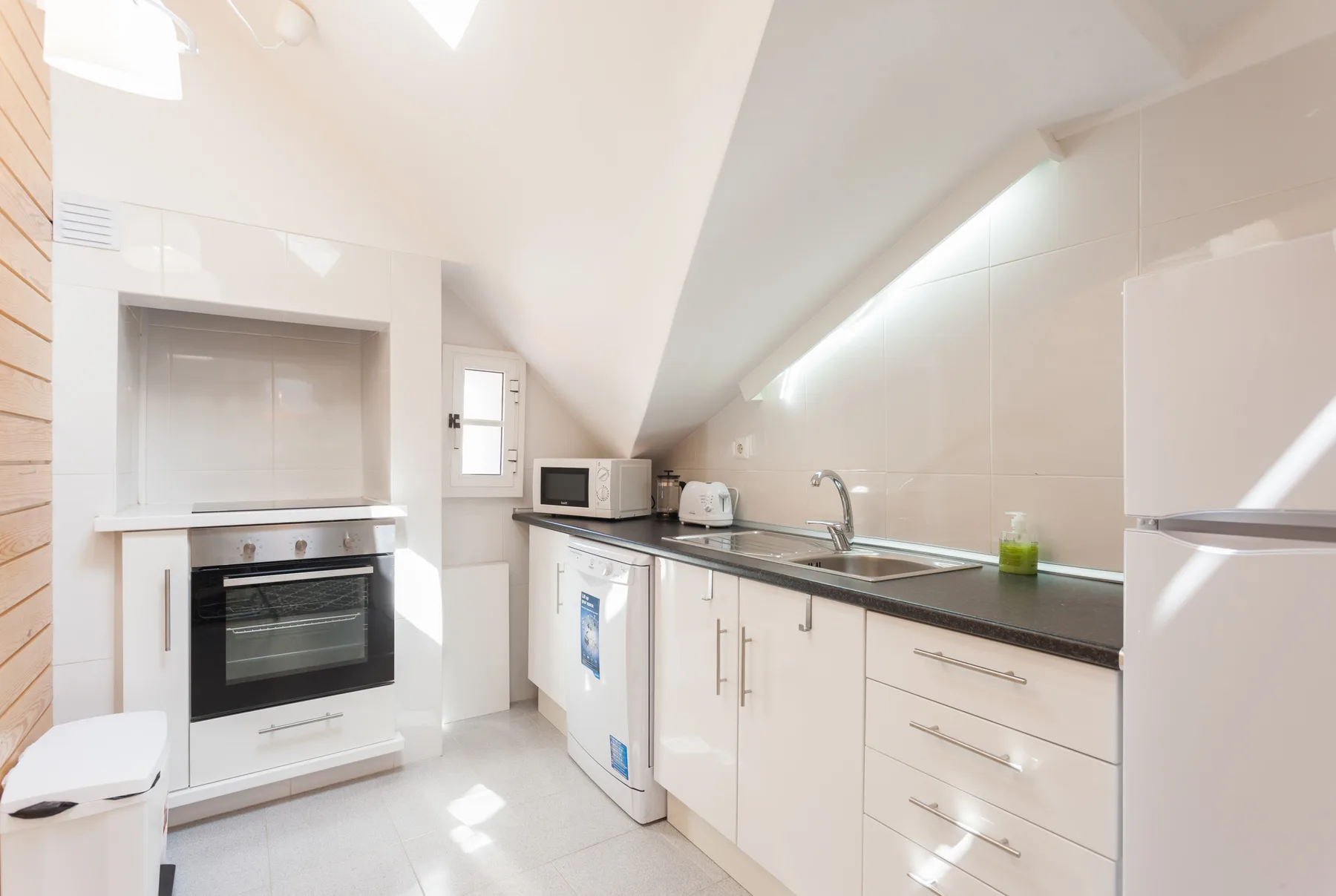 A bright kitchen with white cabinets, a countertop, and built-in appliances.