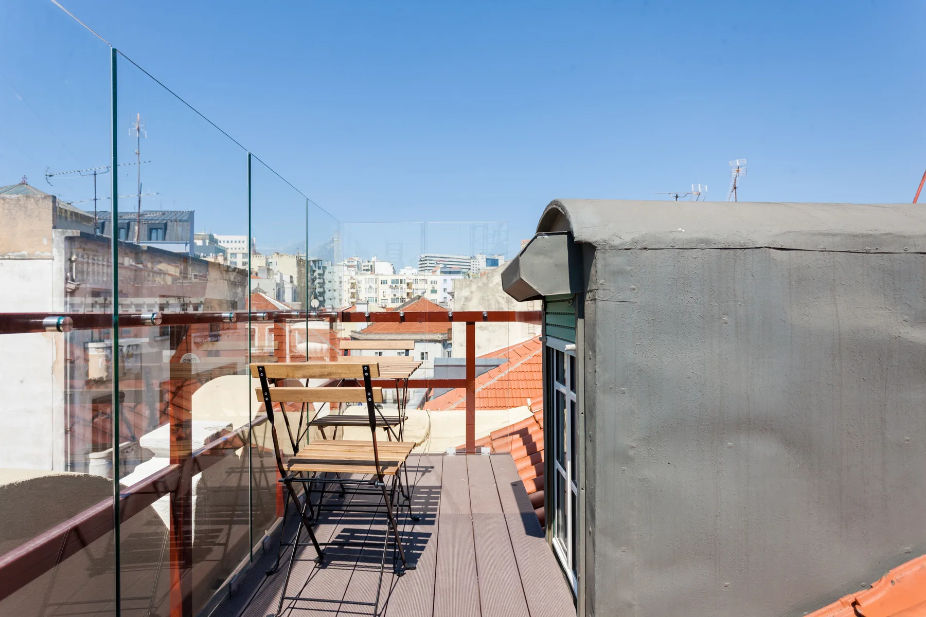A rooftop terrace with outdoor seating and views of nearby buildings.