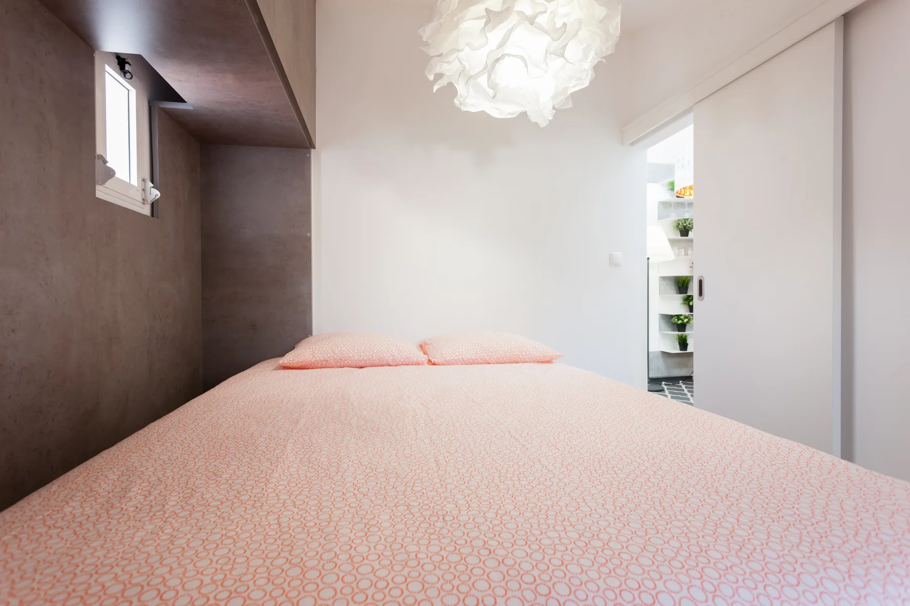 A bedroom with a bed and a small window.