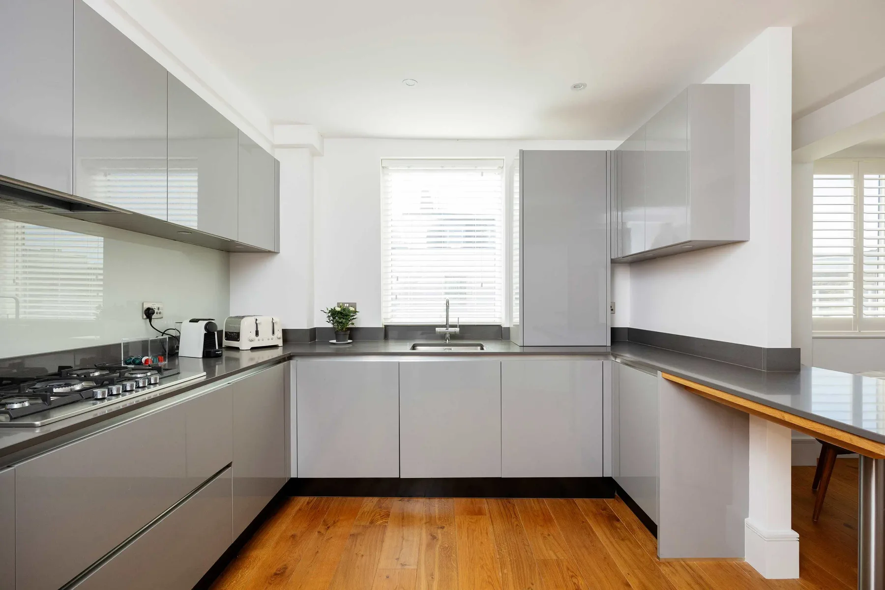 A modern kitchen with gray cabinets, dark countertops, and a central window.
