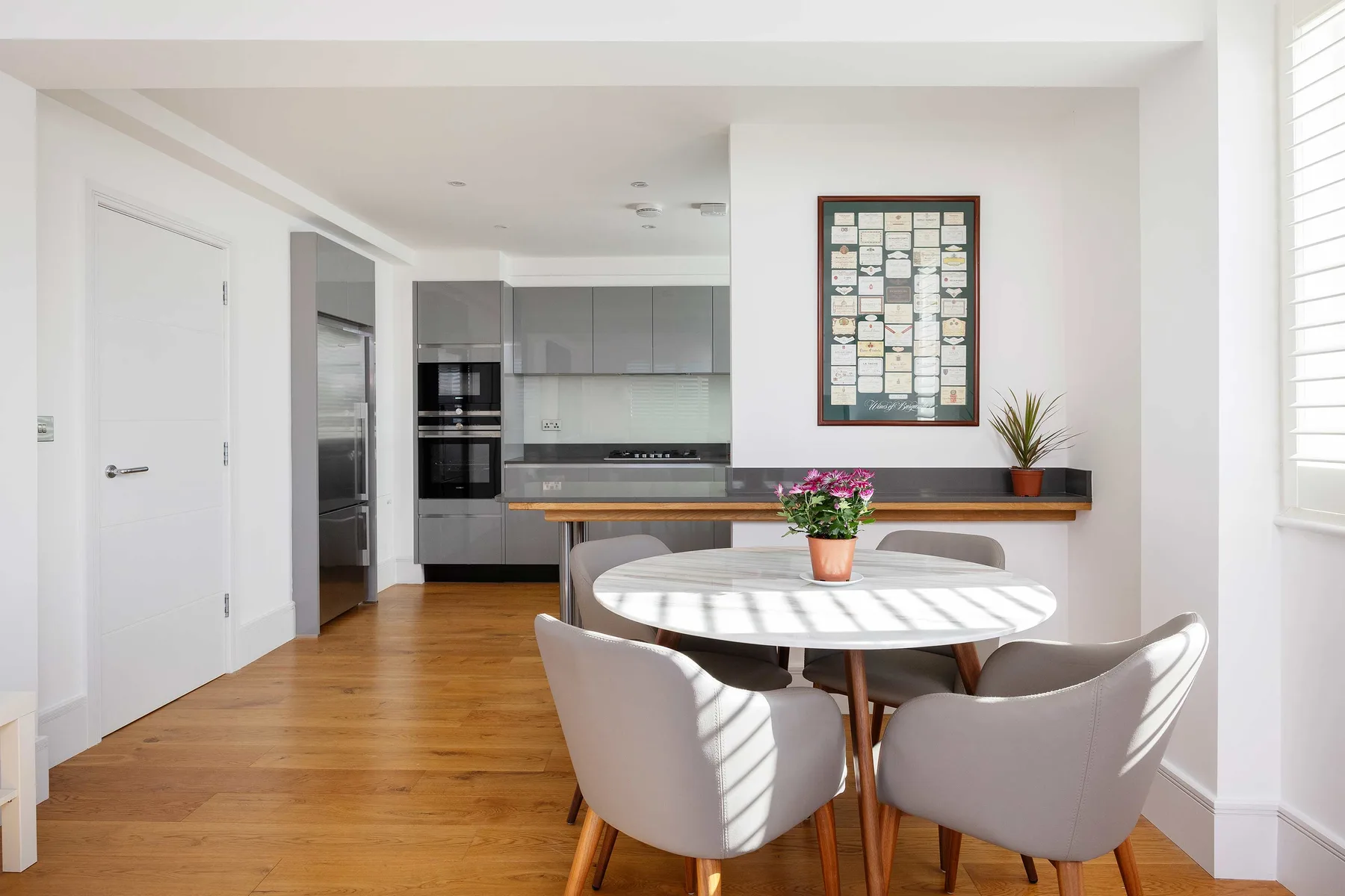 An open-plan dining area and kitchen with a round table and gray cabinetry.