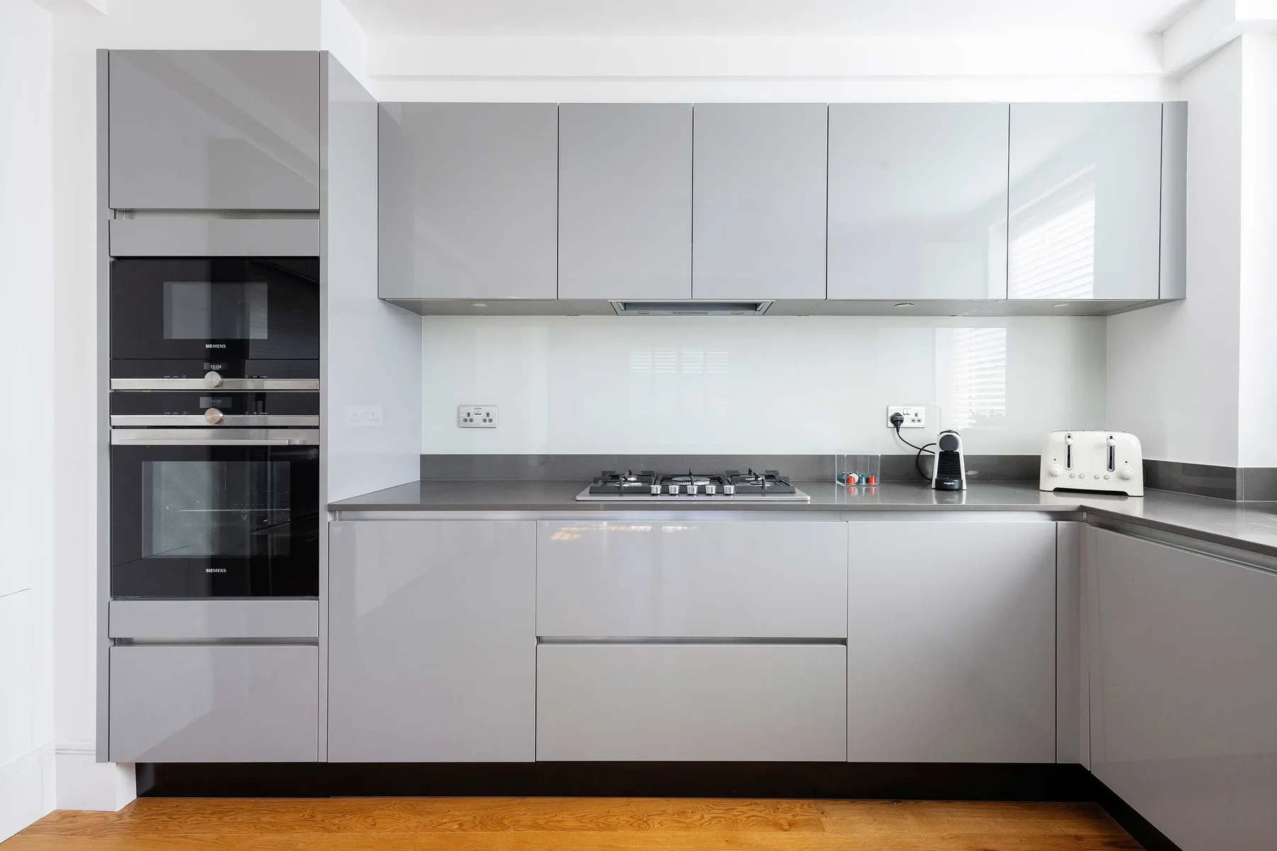 A modern kitchen with gray cabinets, a cooktop, and built-in appliances.