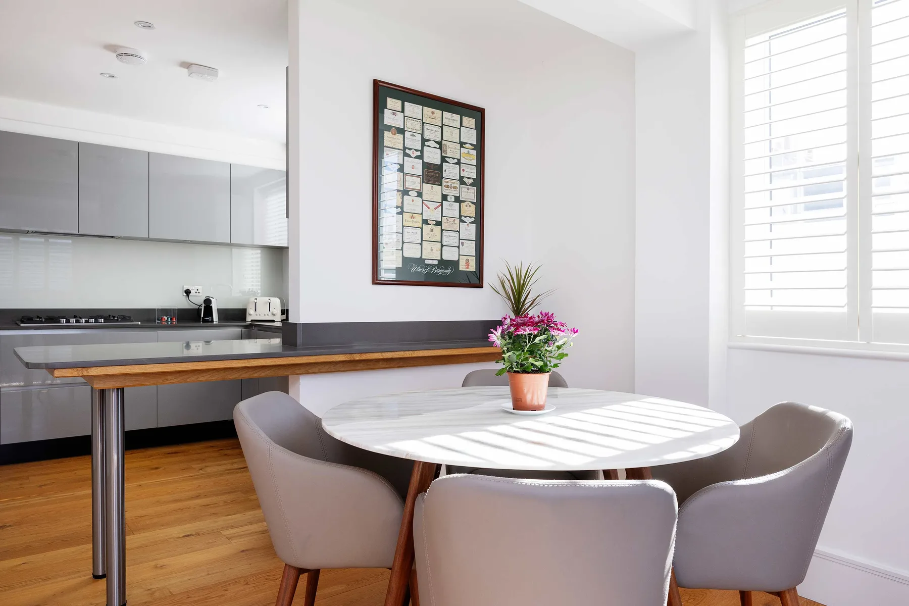 A bright dining area with a round table beside a modern kitchen.