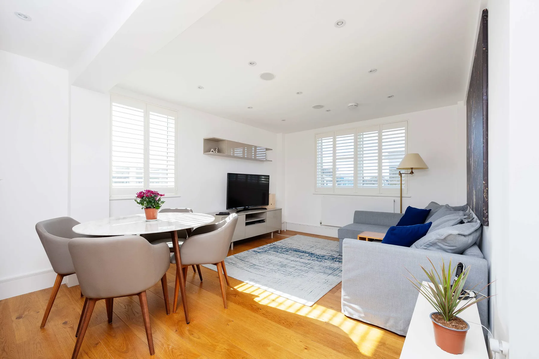 A bright living room with a dining area, television, and seating.