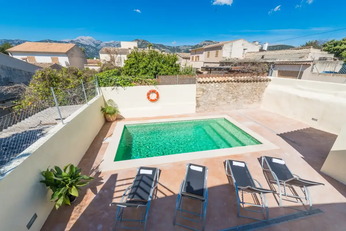 A rooftop pool area with lounge seating and surrounding buildings.