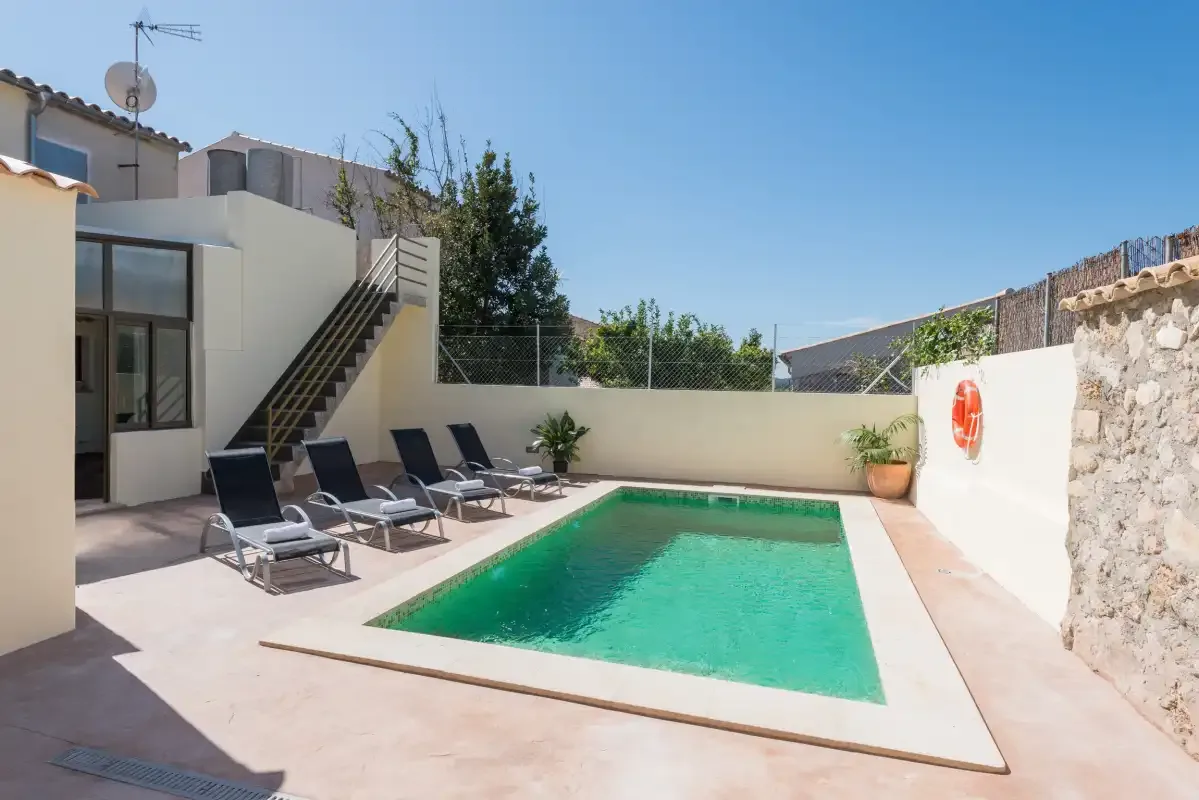 An outdoor swimming pool beside a patio with lounge seating.