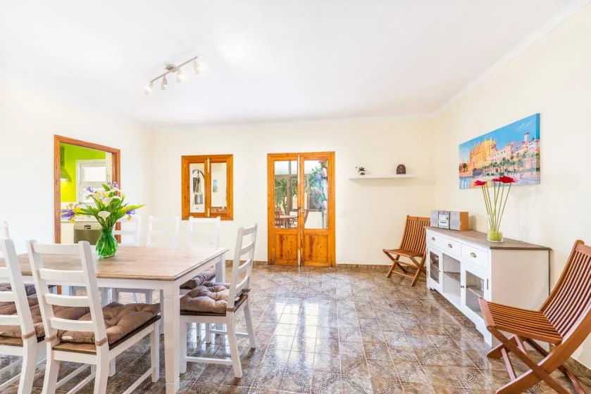 A bright dining and sitting room with a table, chairs, and a white sideboard.