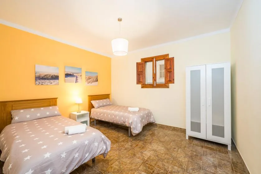 A bedroom with two beds, a wardrobe, and a small window.