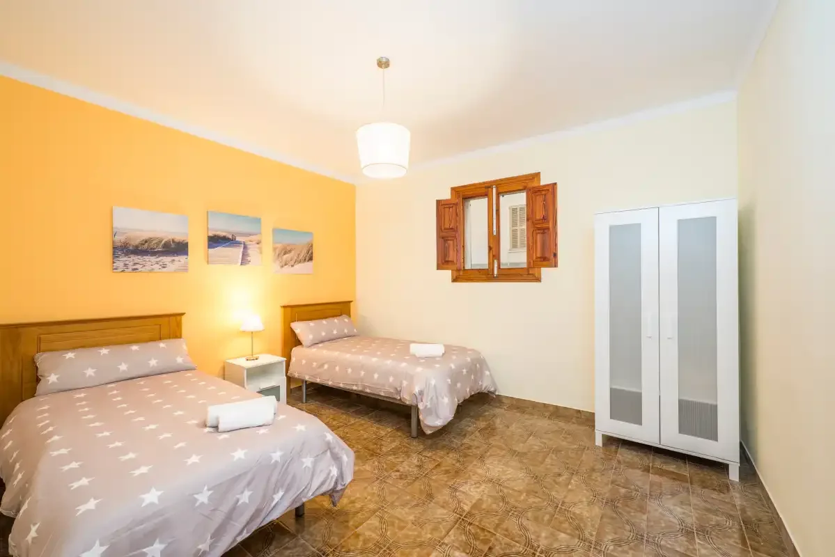 A bedroom with two beds, a wardrobe, and a small window.