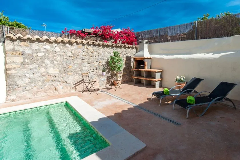 An outdoor patio features a small pool, lounge seating, and a built-in grill.