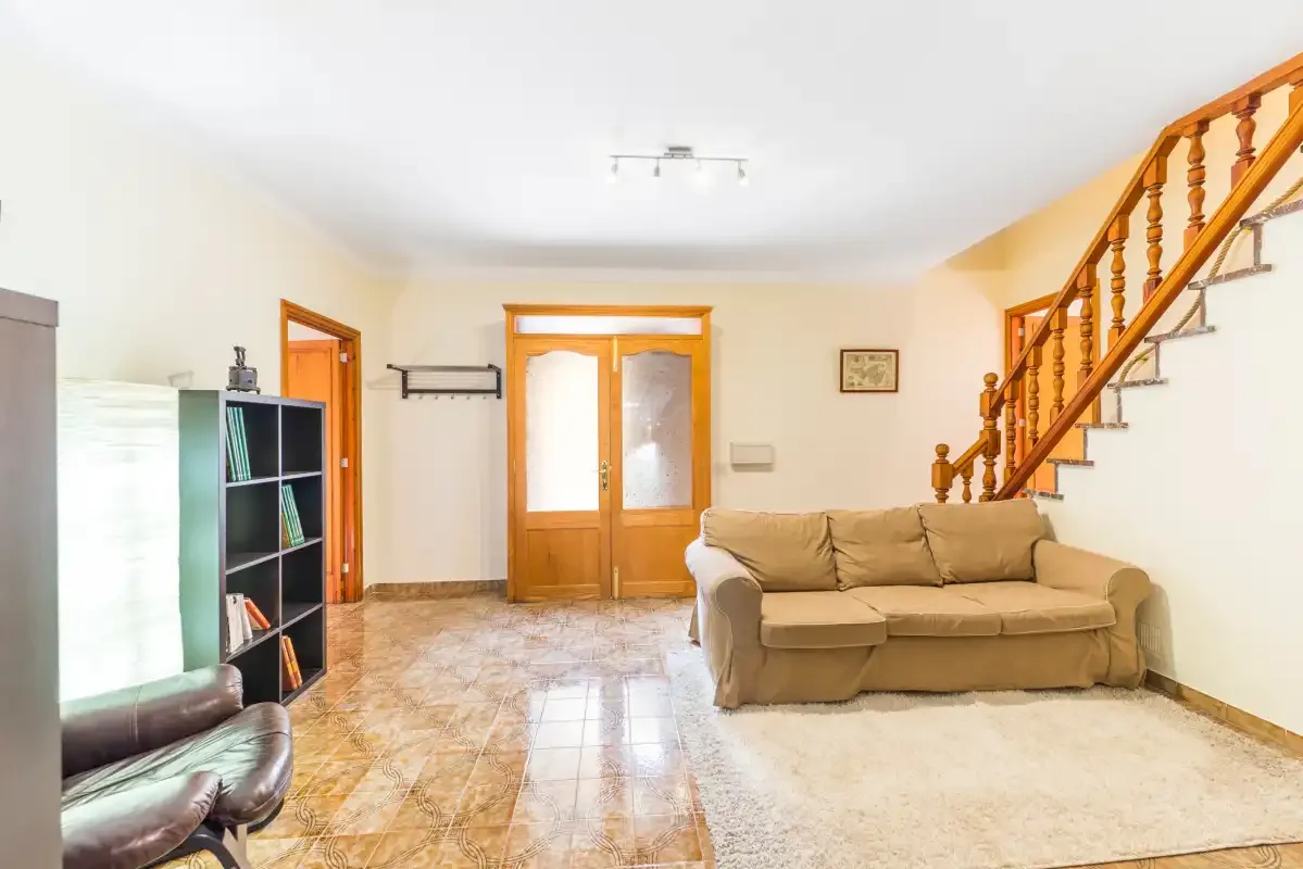Living room with beige seating, a television, and a staircase.