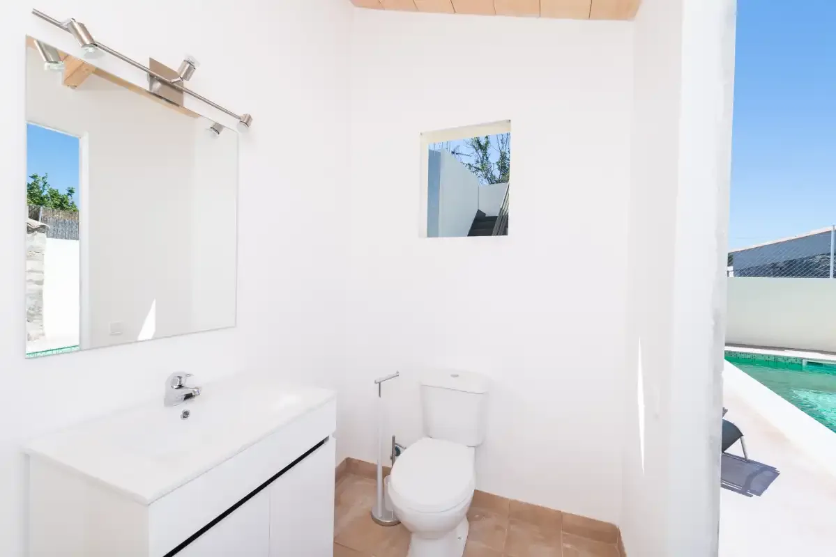 A bright bathroom with a sink and toilet beside a pool.