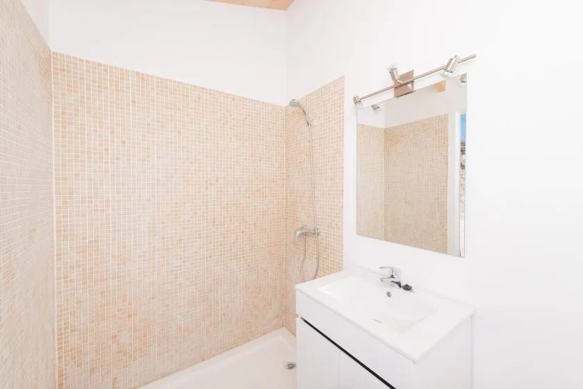 A bright bathroom with a tiled shower area and a white sink.