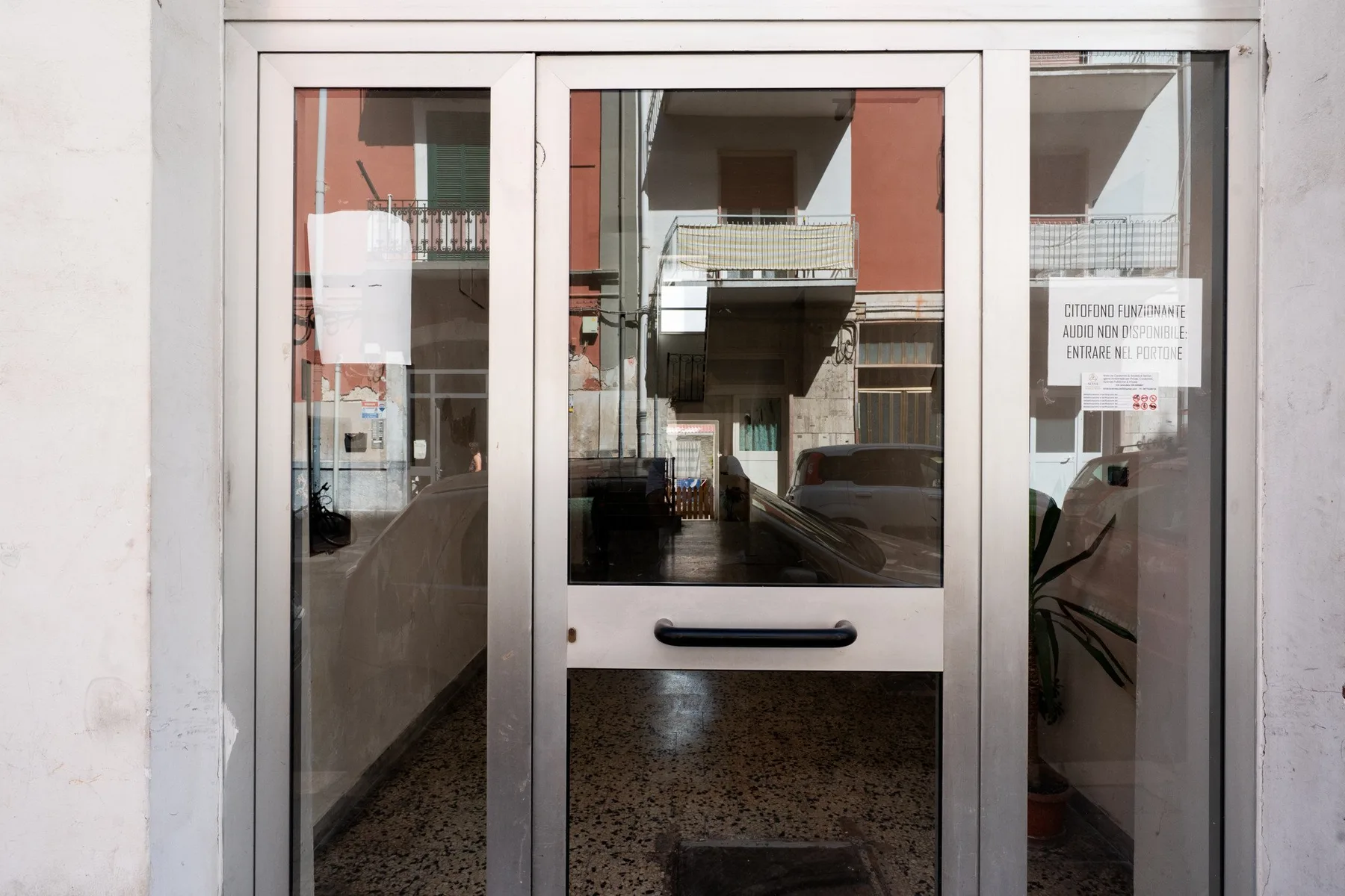A glass entrance door reflects nearby buildings and the street.