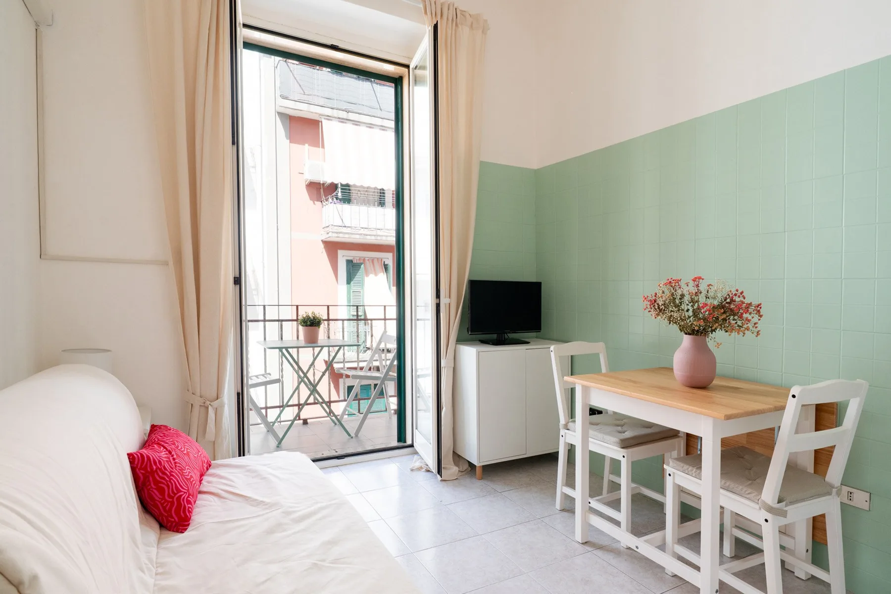 A bright dining area with a wooden table and balcony doors.