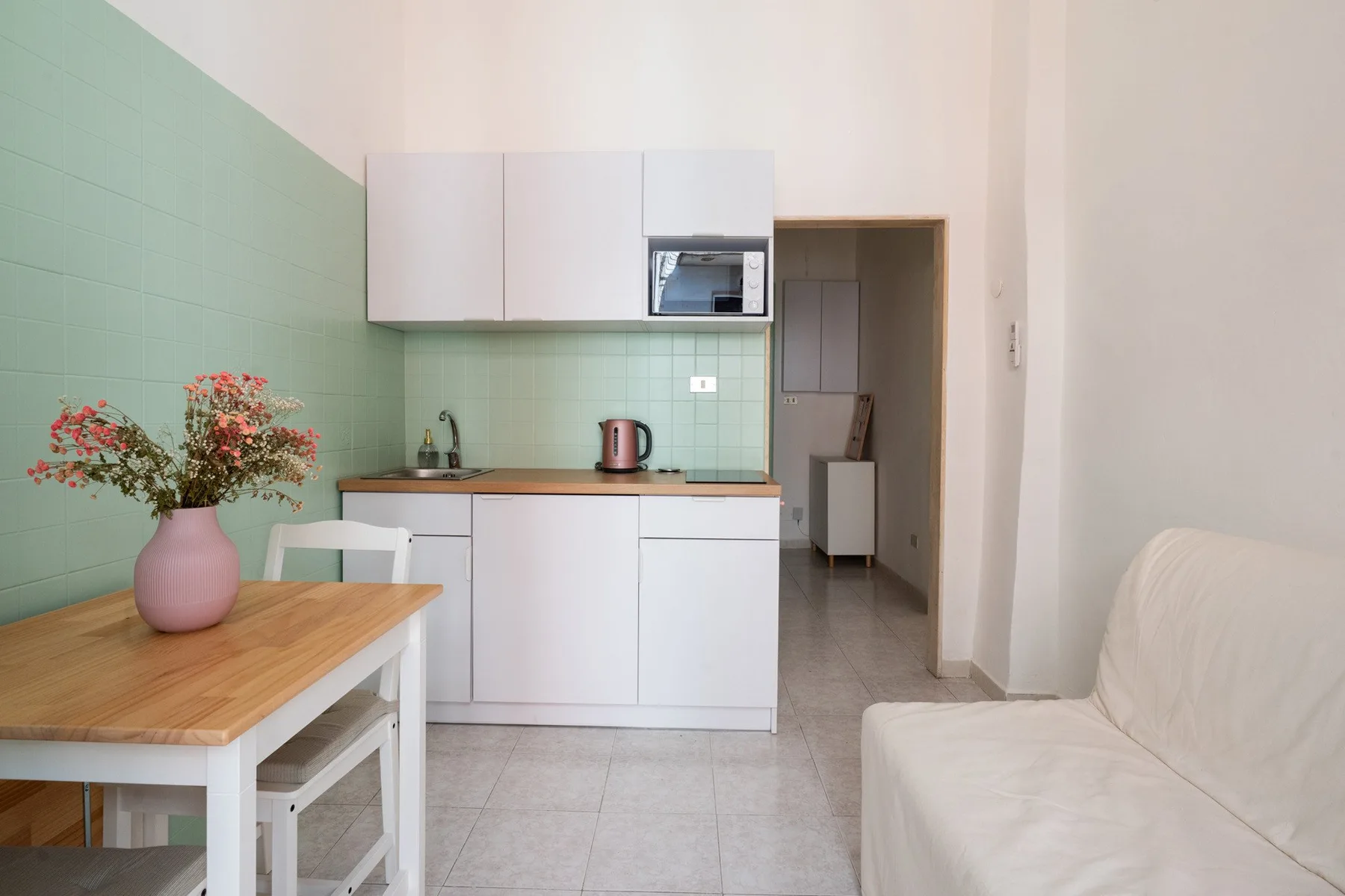 A compact kitchen with white cabinets, a counter, and a small dining table.