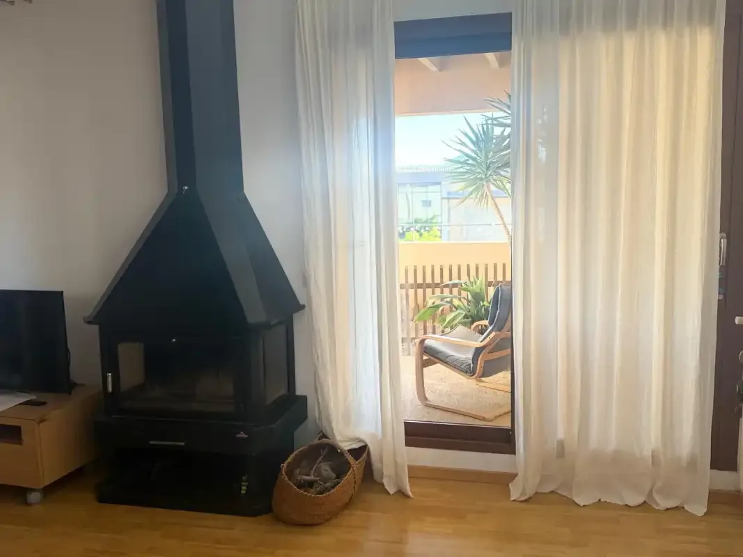 Una sala de estar con chimenea y puertas acristaladas con cortinas que dan a un balcón.