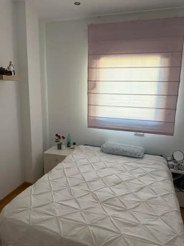 Un dormitorio con una cama bajo una ventana con persiana.
